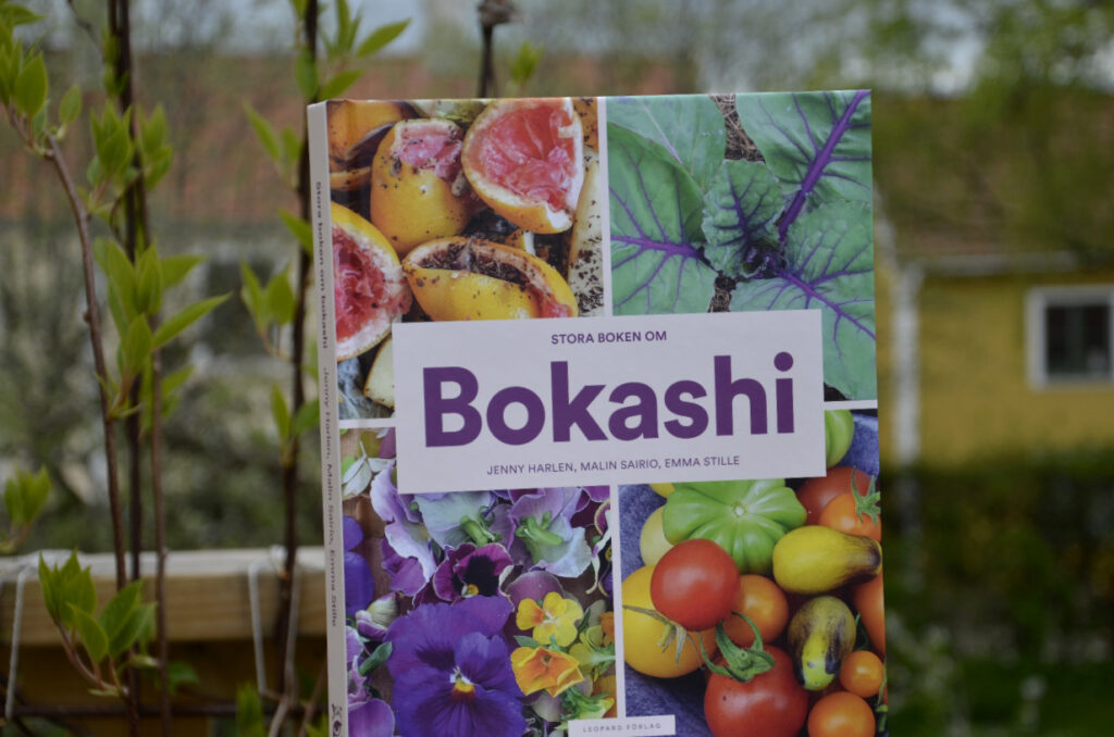 Stora boken om bokashi. Bild på boken med grönska i bakgrunden. 