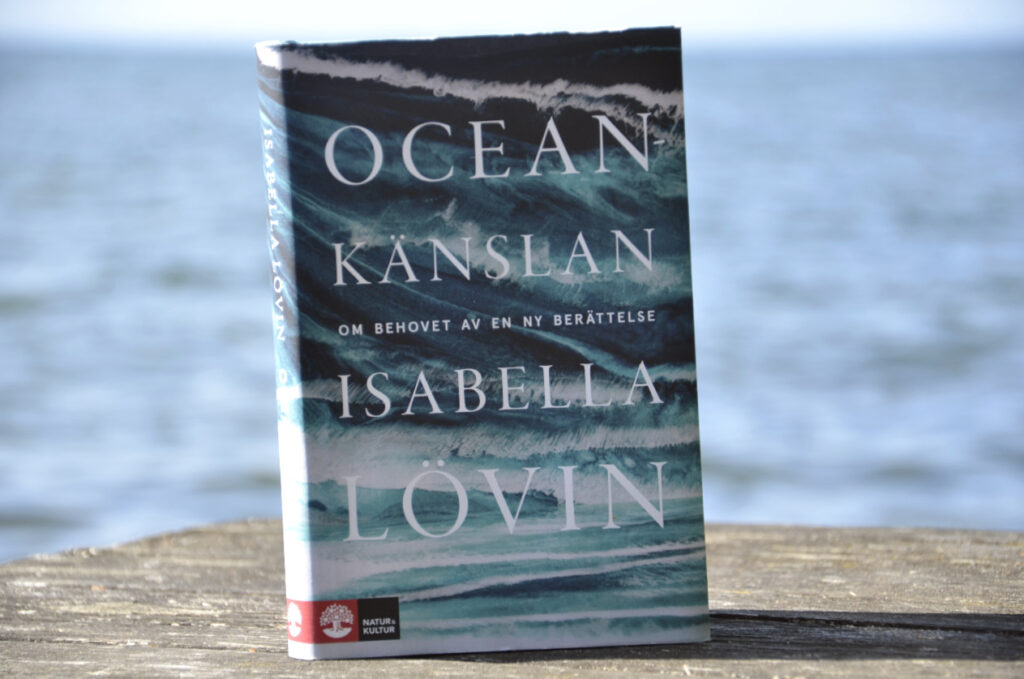 Oceankänslan av Isabella Lövin. Bild på boken Oceankänslan med Vättern i bakgrunden. 