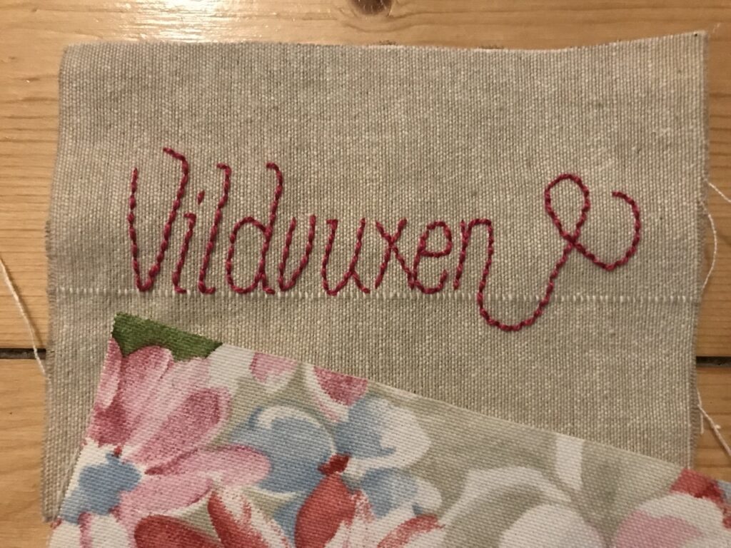 Återförvildning. Bild på broderi där det står "Vildvuxen".